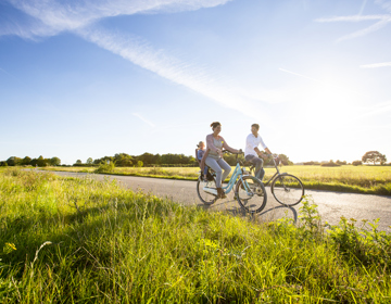 Een gezin fietst op een zonnige avond over een weg