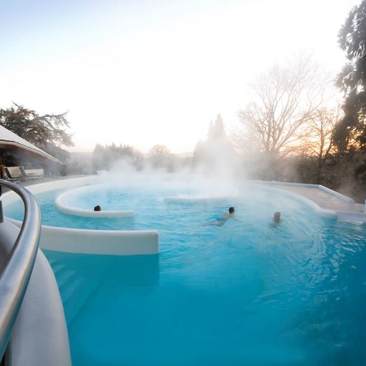 Thermaal buitenbad met stroomversnelling bij wellnesscentrum, waar de damp van het water afkomt.